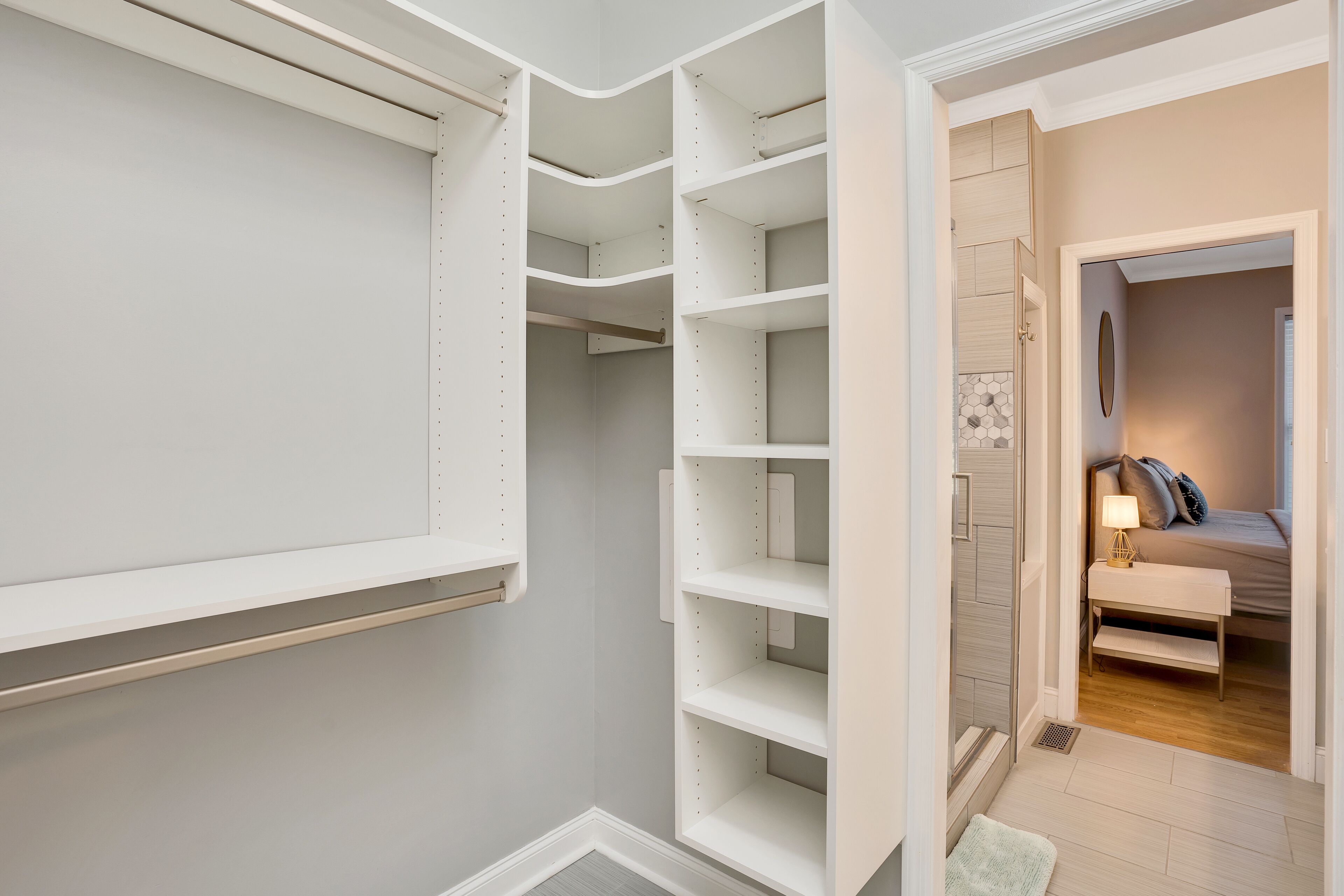 Ein begehbarer Kleiderschrank mit offenen Regalen und einer Tür zum Schlafzimmer.