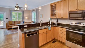 A modern kitchen with granite countertops, wooden cabinets, a built-in oven, and a dishwasher.