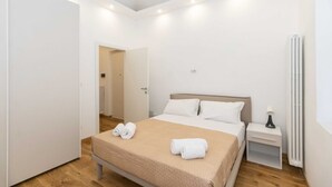 A bedroom with a bed, a nightstand, and a radiator.