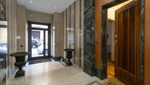 A hotel lobby with marble flooring, a wooden door, and a reception desk.