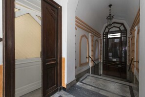 A hallway with a wooden door, a glass door, and a marble floor.