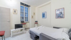A bedroom with a bed, a desk, a chair, a television, and a window. - GuestHost - Cozy apartment of 50 sqm, able to accommodate up to 4 people, located on the first floor of a building without elevator. The location is great! We are about 300 meters from the Cathedral of San Lorenzo, 200 meters from Palazzo Ducale , 600 fr (Genova)