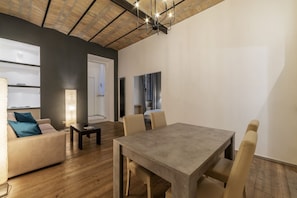 A modern living room with a dining table, sofa, and a large window.
