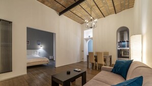Una sala moderna con un sofá, una mesa de centro, un comedor y una cocina visible a través de un arco.