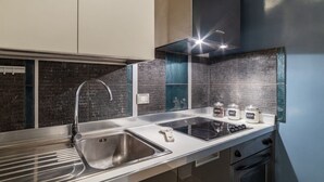 Una cocina moderna con un lavamanos de acero inoxidable, una cocina por inducción y un horno empotrado.