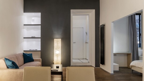 Una habitación moderna con sofá, mesa de centro, lámpara, armario y puerta que da a un baño.