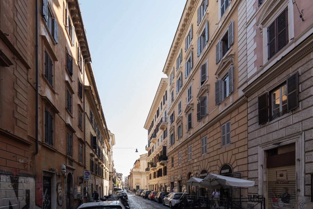 Una stretta via fiancheggiata da auto parcheggiate e palazzi.
