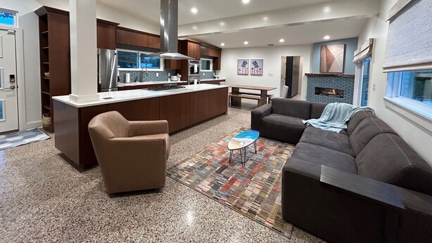 A modern kitchen with a central island, a dining area with a table and chairs, and a living room with a sofa and a coffee table.