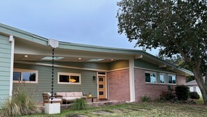 A two-story house with a covered porch, a brick exterior, and a small front yard.
