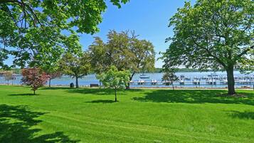 A grassy park area with trees and a lake in the background.