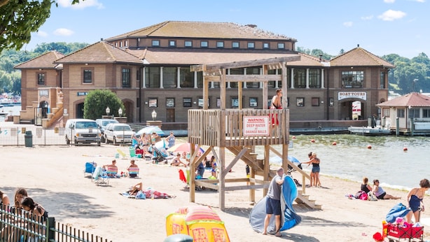 Una playa con una torre de salvavidas, un edificio con un letrero que dice 'Boat Tours', y una vista despejada del agua.