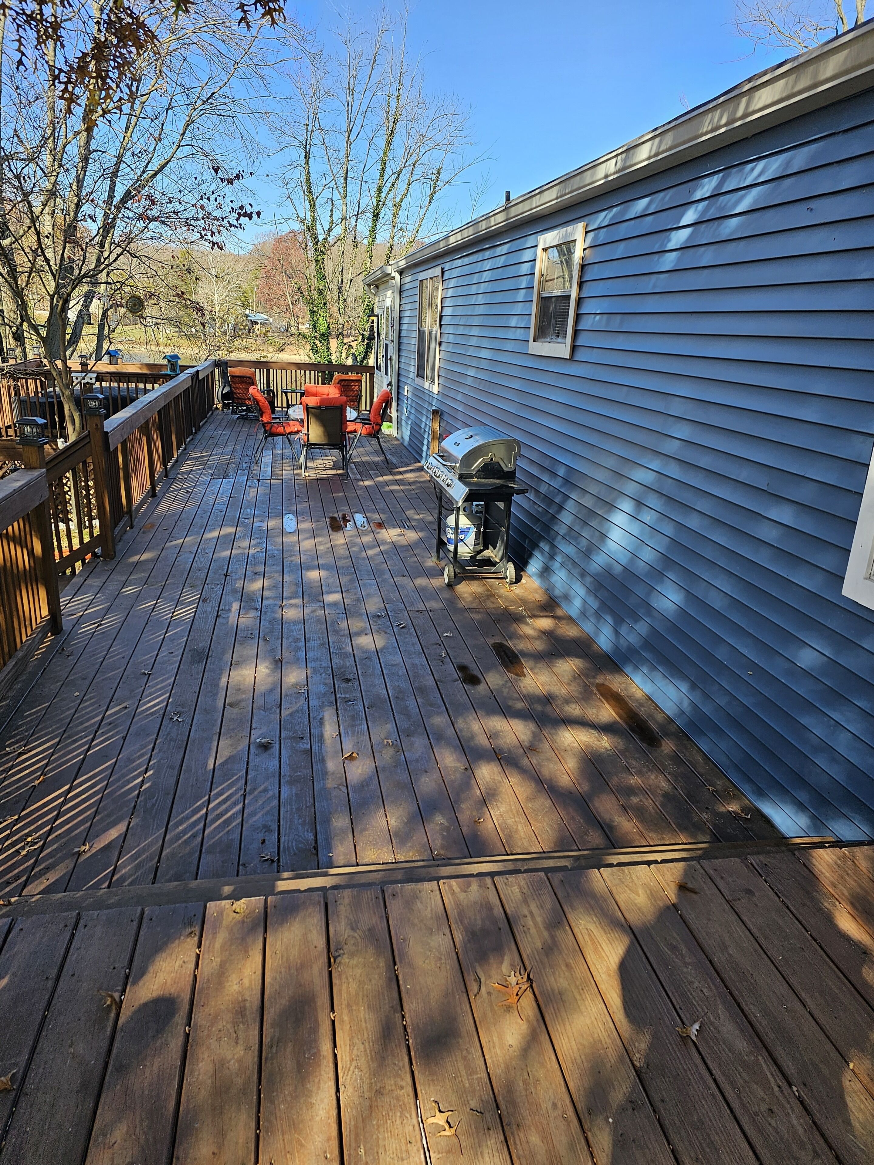 A wooden deck with a barbecue grill and outdoor furniture.