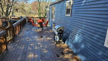 A wooden deck with a barbecue grill and outdoor furniture.