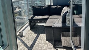 Un balcon avec un canapé noir, une petite table et une lanterne décorative.