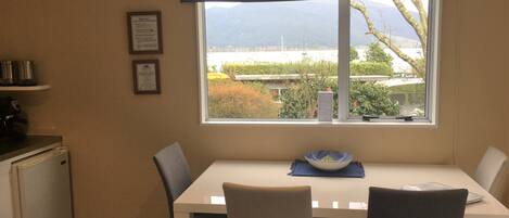 A dining area with a table, chairs, and a view of the outdoors through a large window.