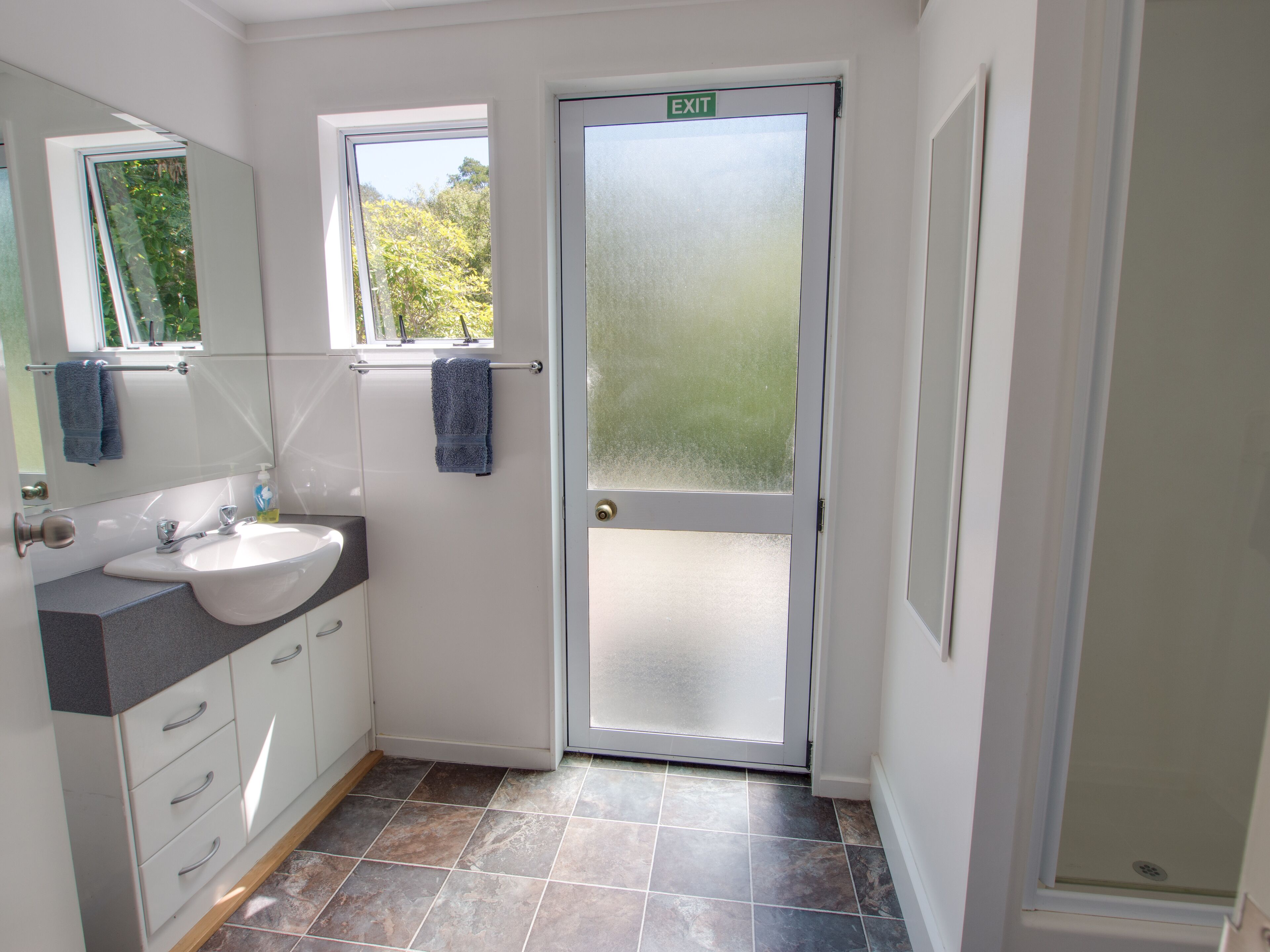 A bathroom with a white sink, mirror, and two towels hanging on a rack.