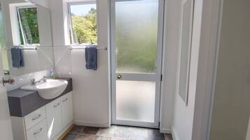 A bathroom with a white sink, mirror, and two towels hanging on a rack.
