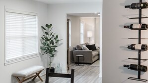 Een moderne woonkamer met een bank, een eettafel met stoelen en een wijnrek aan de muur.
