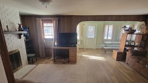 Ein Wohnzimmer mit Kamin, Fernseher und Holzboden.