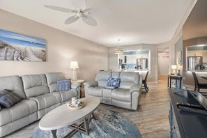 A modern living room with a sofa, coffee table, and a ceiling fan. - Atlantis 205B - Beachers Landing - Renovated (St. Augustine Beach)