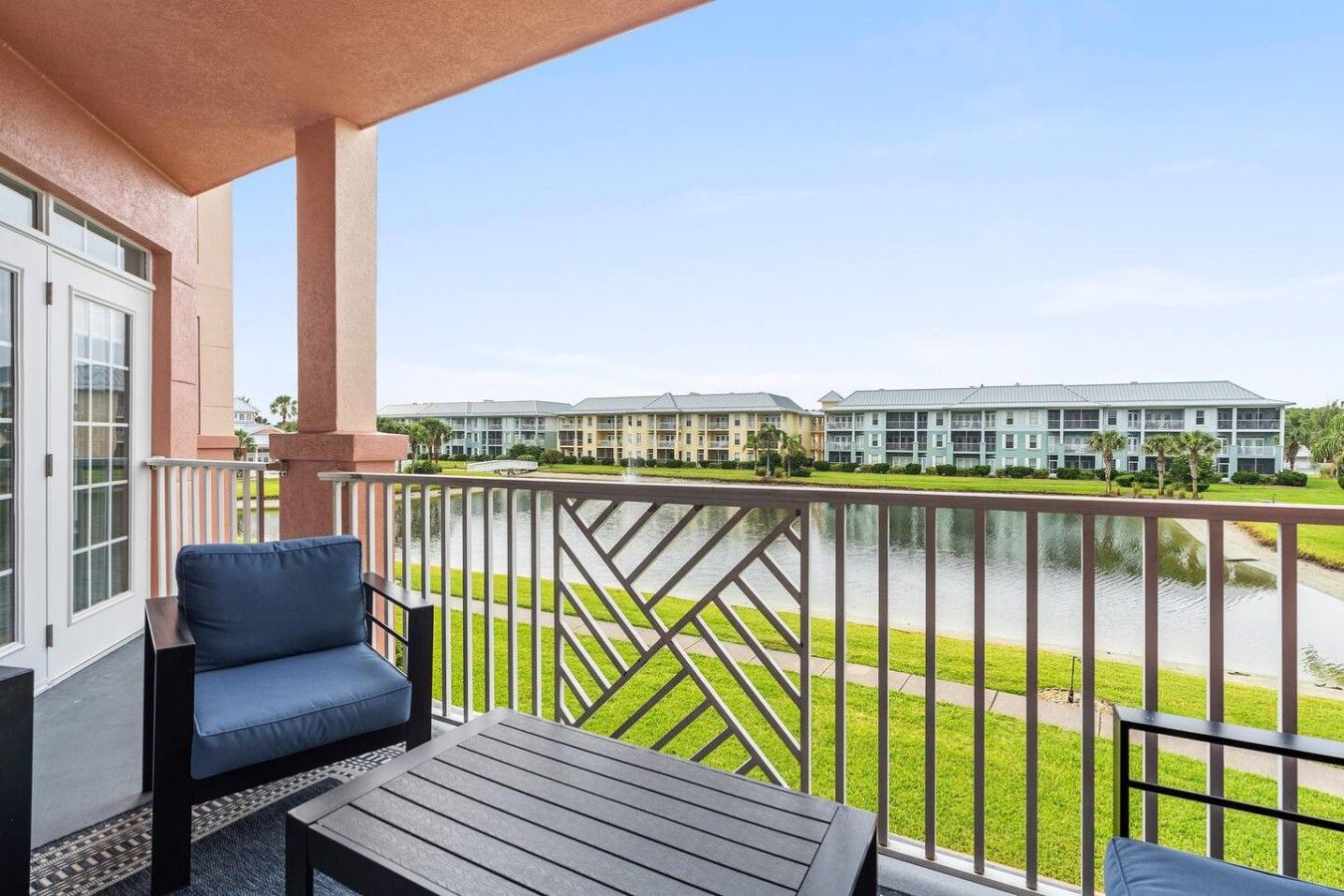 A balcony with a view of a water body and a row of buildings in the background.