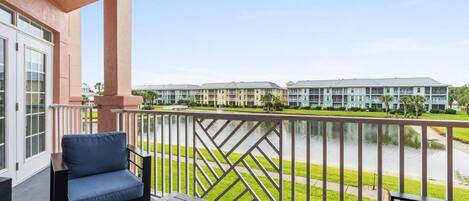 A balcony with a view of a water body and a row of buildings in the background.