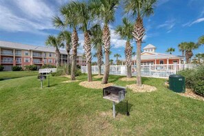 A hotel with a pool, palm trees, and a fenced area. - Atlantis 205B - Beachers Landing - Renovated (St. Augustine Beach)