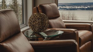 Un sofá de cuero marrón con una mesa de centro de vidrio y una esfera decorativa.
