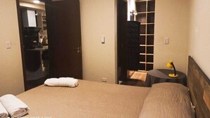 Ein Hotelzimmer mit einem Bett, einem Nachttisch mit Lampe, einem Kleiderschrank und einem durchgegangenen Tür erkennbaren Badezimmer.