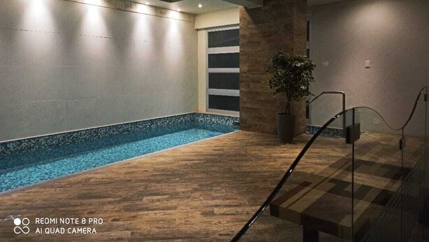 Ein moderner Innenpoolbereich mit Holzboden, Steinwand und einer Topfpflanze.