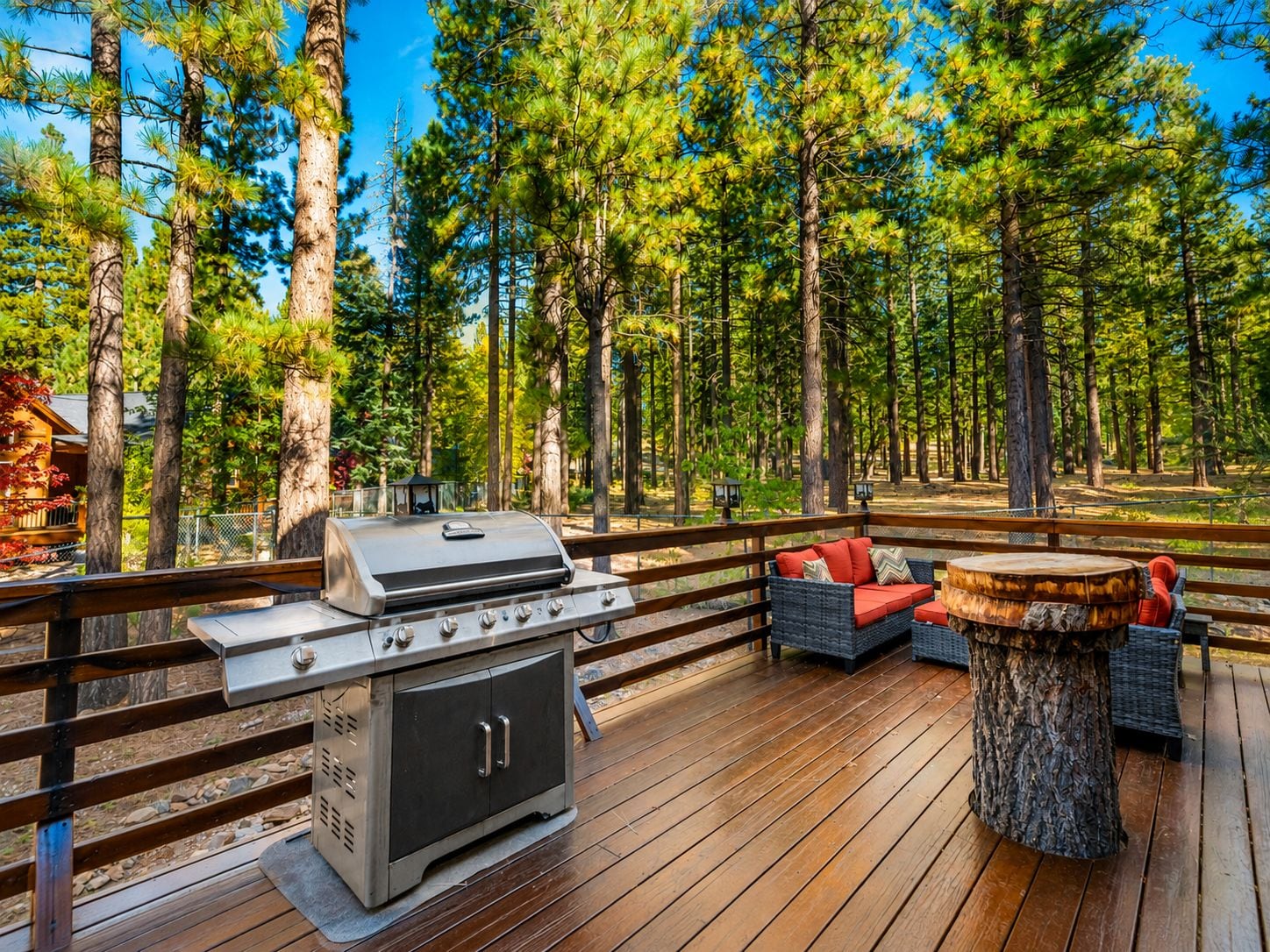 Eine Terrasse im Freien mit Grill, Korbmöbeln und einem Holztisch.