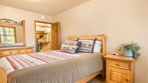 A bedroom with a bed, wooden nightstands, a dresser, a mirror, and a potted plant. - Starlight Summit (Big Bear Lake)