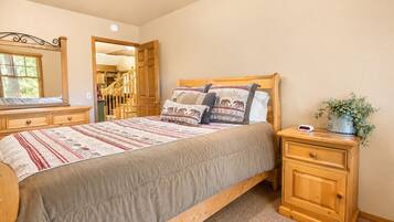 Un dormitorio con una cama, mesitas de noche de madera, un aparador, un espejo y una planta en maceta.