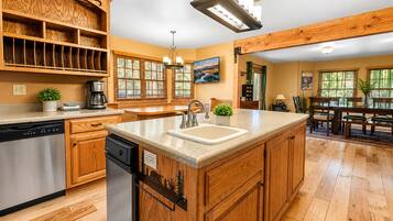 Una cocina con armarios de madera, lavavajillas, una isla grande con un fregadero y un comedor con mesa y sillas.