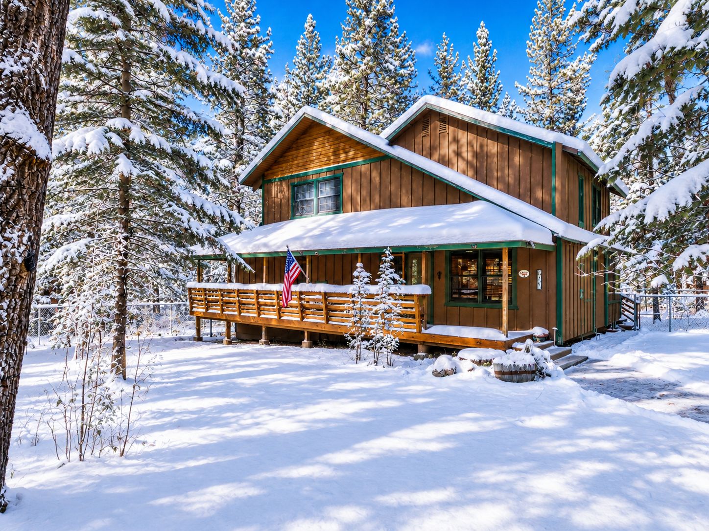 Una cabaña de madera con porche, rodeada de árboles cubiertos de nieve.