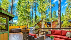 A wooden deck with outdoor furniture, a grill, and a view of the surrounding forest. - Starlight Summit (Big Bear Lake)