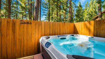 Ein Whirlpool in einem Holzdeckbereich, im Hintergrund ein Holzzaun mit der Aufschrift 'Towels'.