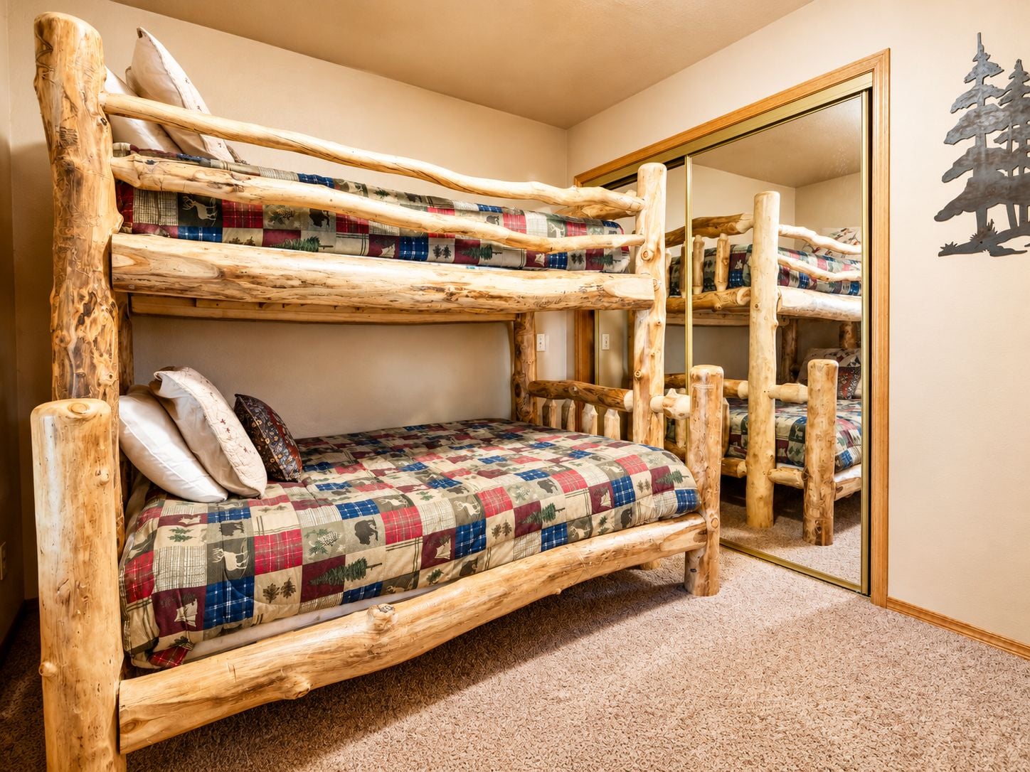 A bunk bed with a quilted bedspread and pillows, a mirror, and a wall decoration.