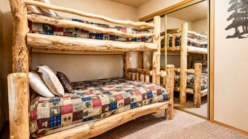 A bunk bed with a quilted bedspread and pillows, a mirror, and a wall decoration.
