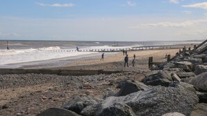 A rocky beach with a wooden pier extending into the sea, a sandy shore, and a clear sky. - The Coastal Hideaway (Hornsea)