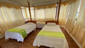 Quarto com duas camas de solteiro, cabeceiras de madeira e piso de madeira.