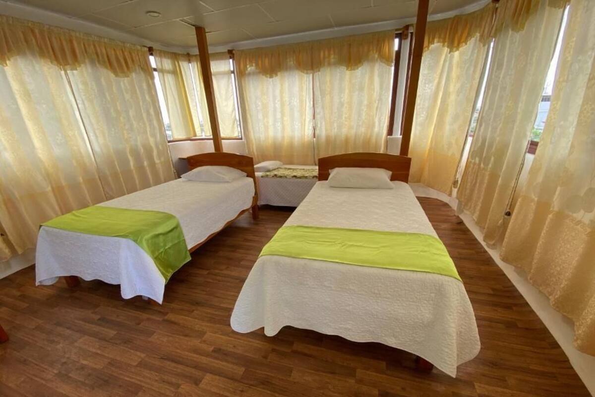 Ein Zimmer mit zwei Einzelbetten, Holz-Kopfteilen und Holzboden.