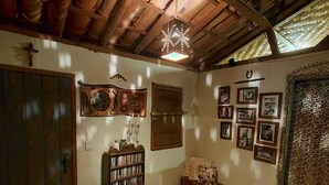 Une pièce rustique avec un plafond en bois, une bibliothèque, des tableaux encadrés et un rideau à motifs.