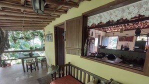 Une pièce chaleureuse avec un plafond en bois, un banc agrémenté de coussins, une table à manger avec des chaises et une grande fenêtre donnant sur un paysage verdoyant.