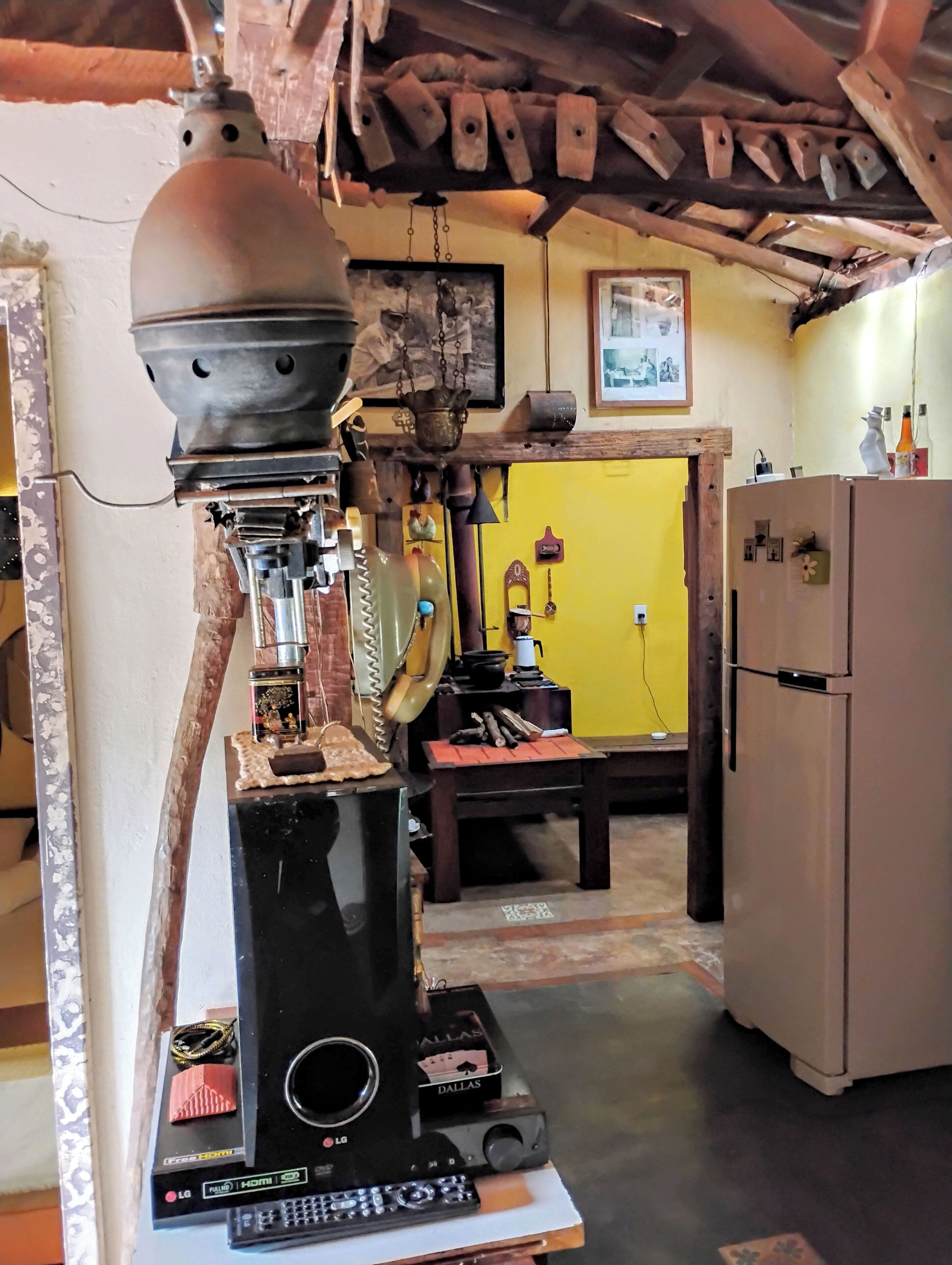 A kitchen with a vintage coffee grinder, a refrigerator, and a yellow wall.
