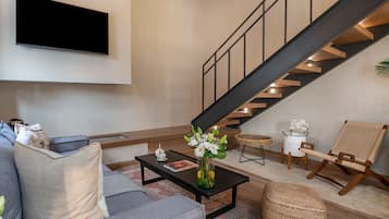 A modern living room with a sofa, coffee table, and a staircase.