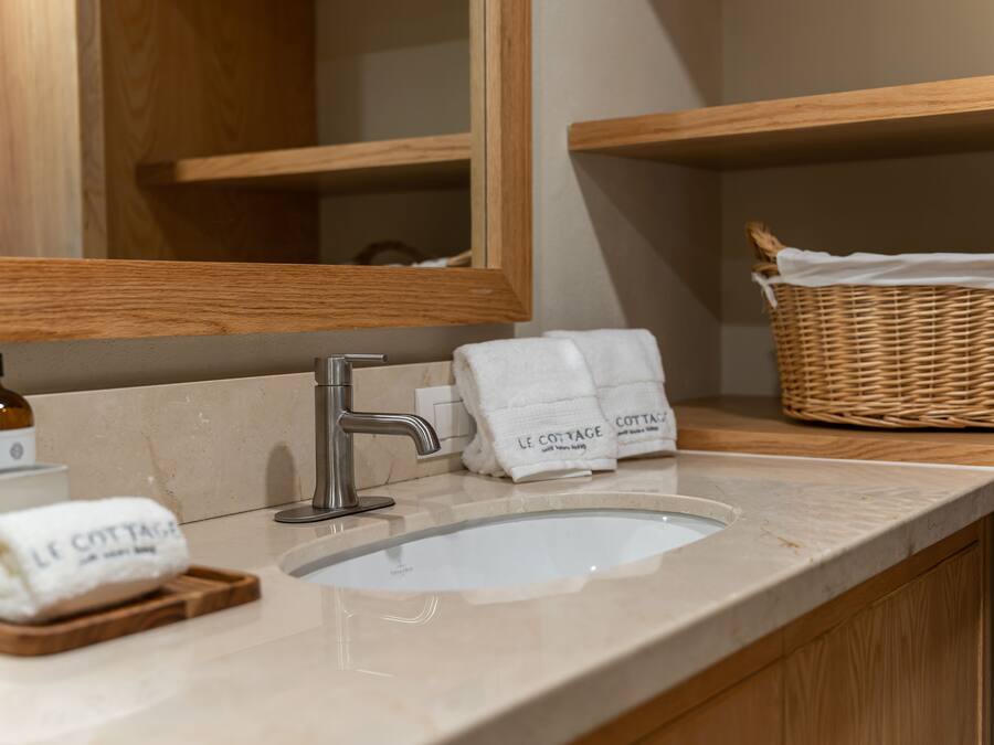 A bathroom with a marble sink, wooden vanity, and a wicker basket.