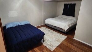 Un dormitorio con dos camas, ventilador de techo y piso de madera.