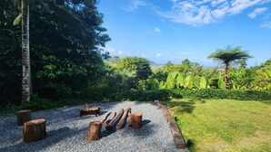 A garden with a gravel path, wooden stumps, and lush greenery. - NEW -The Sugar Shack, Ocean views over cane fields from your outdoor Spa Bath  (Miallo)