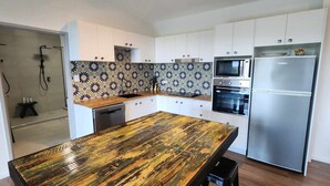 A modern kitchen with white cabinets, a wooden island, a stainless steel refrigerator, and a patterned backsplash. - NEW -The Sugar Shack, Ocean views over cane fields from your outdoor Spa Bath  (Miallo)